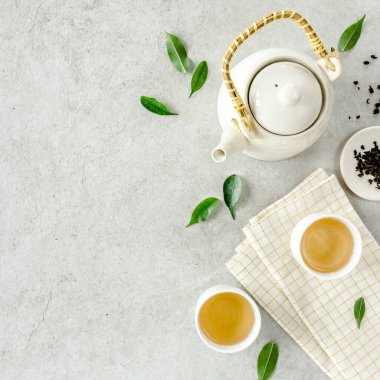 İki beyaz çay fincanı ve yeşil çay yapraklı çaydanlık ile bitki çayı. Düz yerde, üst tarafta. Çay konsepti