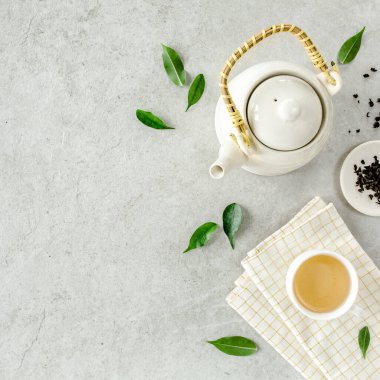 İki beyaz çay fincanı ve yeşil çay yapraklı çaydanlık ile bitki çayı. Düz yerde, üst tarafta. Çay konsepti