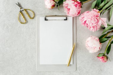 Sahte davetiye, boş kağıt tebrik kartı ve gri taş masadaki şakayıklar. Çiçek arkaplanı. Düz yatış, üst görünüm.