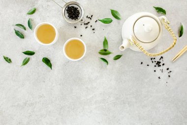 İki beyaz çay fincanı ve yeşil çay yapraklı çaydanlık ile bitki çayı. Düz yerde, üst tarafta. Çay konsepti