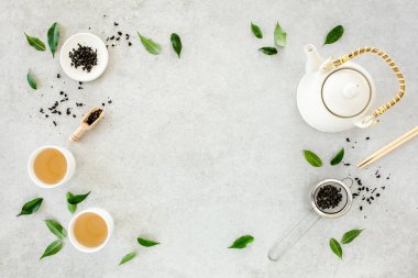İki beyaz çay fincanı ve yeşil çay yapraklı çaydanlık ile bitki çayı. Düz yerde, üst tarafta. Çay konsepti