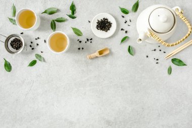 İki beyaz çay fincanı ve yeşil çay yapraklı çaydanlık ile bitki çayı. Düz yerde, üst tarafta. Çay konsepti