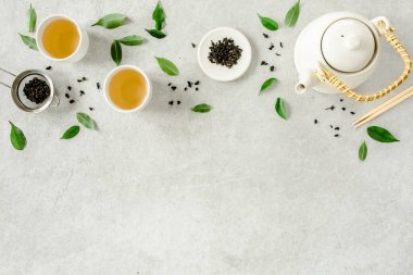 İki beyaz çay fincanı ve yeşil çay yapraklı çaydanlık ile bitki çayı. Düz yerde, üst tarafta. Çay konsepti