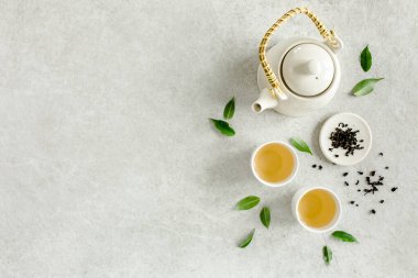 İki beyaz çay fincanı ve yeşil çay yapraklı çaydanlık ile bitki çayı. Düz yerde, üst tarafta. Çay konsepti
