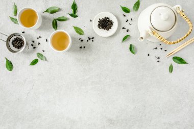 İki beyaz çay fincanı ve yeşil çay yapraklı çaydanlık ile bitki çayı. Düz yerde, üst tarafta. Çay konsepti
