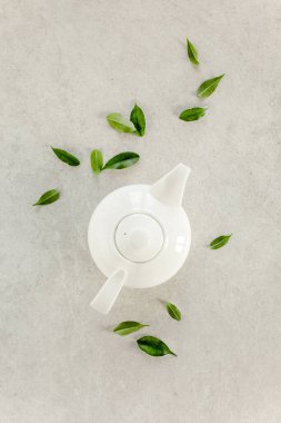 Yeşil çay yapraklı, beyaz çaydanlıkta bitki çayı. Düz yerde, üst tarafta. Çay konsepti