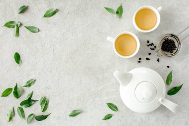 İki beyaz çay fincanı ve yeşil çay yapraklı çaydanlık ile bitki çayı. Düz yerde, üst tarafta. Çay konsepti