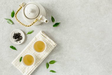 İki beyaz çay fincanı ve yeşil çay yapraklı çaydanlık ile bitki çayı. Düz yerde, üst tarafta. Çay konsepti