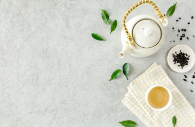İki beyaz çay fincanı ve yeşil çay yapraklı çaydanlık ile bitki çayı. Düz yerde, üst tarafta. Çay konsepti
