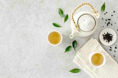 İki beyaz çay fincanı ve yeşil çay yapraklı çaydanlık ile bitki çayı. Düz yerde, üst tarafta. Çay konsepti