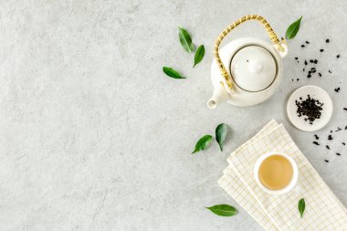 İki beyaz çay fincanı ve yeşil çay yapraklı çaydanlık ile bitki çayı. Düz yerde, üst tarafta. Çay konsepti