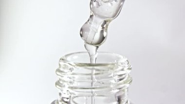 Gri zemin üzerinde yağ damlaları olan kozmetik pipeti