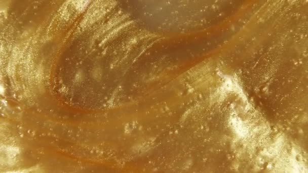 Fondo metallico oro liquido, texture. Sovrapposizione del flusso di vernice liquida giallo scintillante. Movimento, rotazione del prodotto cosmetico. Rallentatore — Video Stock