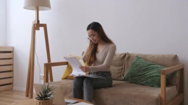 Orta Doğulu uzaktan kumandalı bir kadın. Evrakları kontrol ediyor. Evde kal, uzaktan kumandayı karantinaya al. Yavaş çekim.