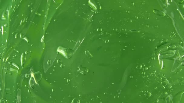Movimento do suco aloe vera. Nata líquida verde, rotação de fluido de gel cosmética em uma superfície. Amostra de produto de beleza skincare com bolhas. Vista superior. Movimento lento. — Vídeo de Stock
