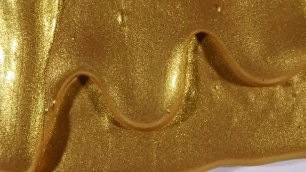 Gold-Gel-Flüssigkeit mit Abfluss an der Oberfläche. Geschmolzenes Gold. Funkelnde gelbe flüssige Farbüberlagerungen. Makroschock — Stockvideo