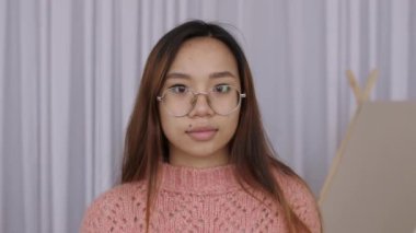 Modern ofis işyerinde poz veren mutlu Orta Doğulu kız öğrencinin yakın plan portresi, neşeyle gülümsüyor. Yavaş çekim.