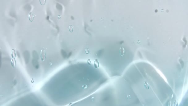 Transparentes blaues Kosmetikgelflüssigkeit mit Blasen, die auf einer weißen Oberfläche abfließen. Makroschock — Stockvideo