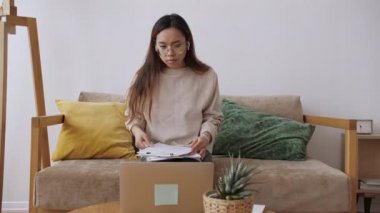 Orta Doğulu kadın uzaktan kumanda, iş arkadaşlarıyla görüntülü görüşme, belgeleri kontrol. Evde kal, uzaktan kumandayı karantinaya al. Yavaş çekim.