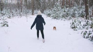 Genç kız av köpeğiyle karlı bir kış ormanında yürüyor. Açık hava yürüyüşü. Mans en iyi arkadaş. Yavaş çekim