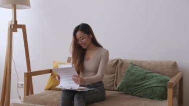 Orta Doğulu uzaktan kumandalı bir kadın. Evrakları kontrol ediyor. Evde kal, uzaktan kumandayı karantinaya al. Yavaş çekim.