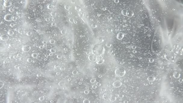 Fond transparent de gel liquide, texture claire du sérum. Mouvement, rotation de l'échantillon de produit de soins de beauté avec bulles. Vue de dessus. Macro Shot — Video