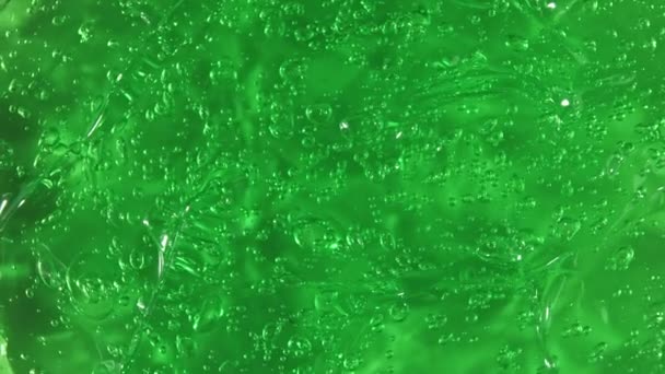 Moto del succo di aloe vera. Crema liquida verde, rotazione di liquido di gel cosmetico su una superficie. Campione di prodotto per la cura della pelle di bellezza con bolle. Vista dall'alto. Rallentatore. — Video Stock