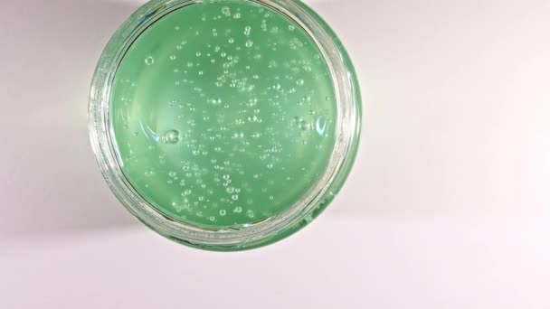 Rörelse av juice aloe vera. Grön flytande kräm, kosmetisk gel vätska rotation på en yta. Skönhet hudvård produktprov med bubblor. Högst upp. Långsamma rörelser. — Stockvideo