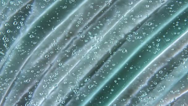 Mouvement, rotation du gel crème liquide texture cosmétique transparente bleue avec bulles. Cosmétiques biologiques, médicaments. Vue de dessus. Macro Shot — Video