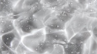 Şeffaf sıvı jel arka plan, açık serum dokusu. Hareket, cilt bakımı, baloncuklu ürün örneği. Üst Manzara. Makro Vuruş