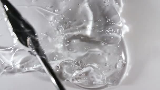 透明な液体ゲルの背景、明確な血清の質感。動き、泡と美容スキンケア製品サンプルの回転。最上階だ。マクロショット — ストック動画