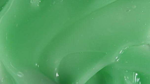 La crema verde líquida, el movimiento cosmético del gel fluido, la rotación sobre la superficie. Muestra de productos de belleza para el cuidado de la piel. Vista superior. Movimiento lento — Vídeo de stock