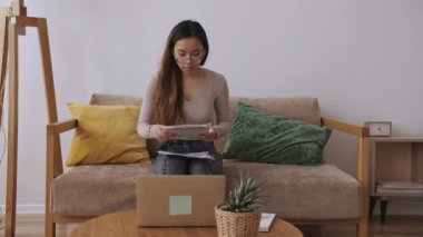 Orta Doğulu uzaktan kumandalı bir kadın. Evrakları kontrol ediyor. Evde kal, uzaktan kumandayı karantinaya al. Yavaş çekim.