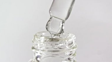 Gri zemin üzerinde yağ damlaları olan kozmetik pipeti