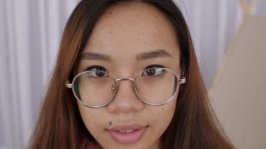 Orta Doğulu gözlüklü genç kadın yüzünü kapatın, kız, öğrenci retro kamerayla fotoğraf çekiyor, panjura basıyor. Kadın fotoğrafçı kamerayı alır ve düğmeye basar. Yavaş çekim.