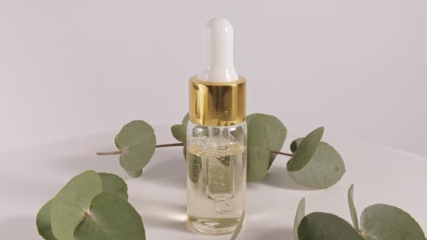 Olej eukaliptusowy z liśćmi na białym tle. Ekstrakt eukaliptusowy, aromatyczny olejek eteryczny. Kosmetyki naturalne do pielęgnacji włosów i skóry. — Wideo stockowe