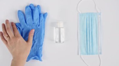 Beyaz tıbbi maskeler ve eldivenli solunum cihazları, beyaz arka planda el dezenfektanı. Yüz maskesi cerrahi, virüs koruması, grip, koronavirüs, COVID-19.