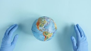 Doktorlar tıbbi eldiven kılıfları veriyor, Dünya 'yı elleriyle koruyorlar. Dünya Salgın Tehlikesi. Çevre koruma, gezegeni kurtarma, barış ve virüs kavramını koruma