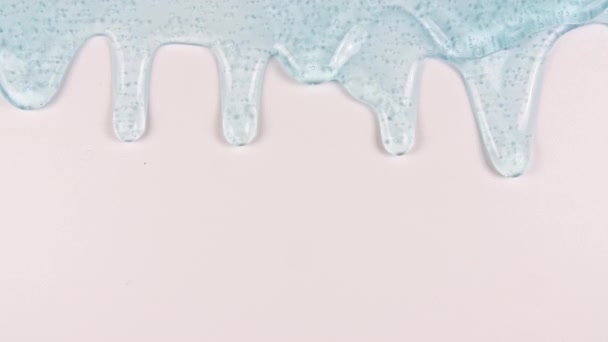 Синя прозора косметична гелева рідина з молекулярними бульбашками, що течуть на рівній білій поверхні. Макро Постріл — стокове відео