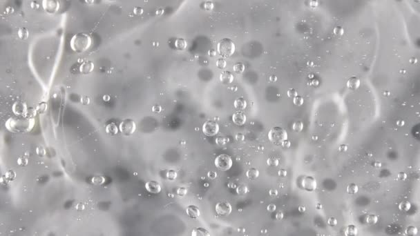 Transparent flytande gel bakgrund, klar serumstruktur. Rörelse, rotation av skönhetshudvård produktprov med bubblor. Högst upp. Makroskott — Stockvideo