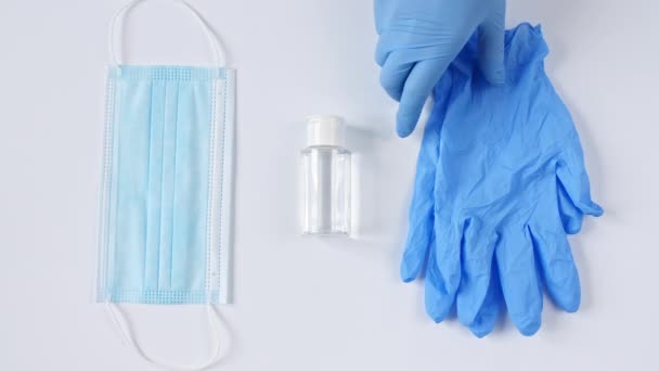 Beyaz tıbbi maskeler ve eldivenli solunum cihazları, beyaz arka planda el dezenfektanı. Yüz maskesi cerrahi, virüs koruması, grip, koronavirüs, COVID-19. — Stok video