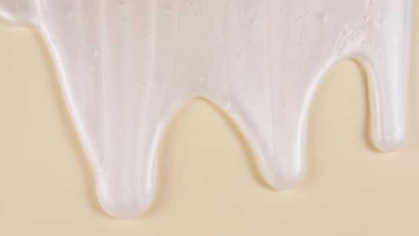 Білий косметичний гелевий рідкий крем з молекулярними бульбашками, що течуть на звичайній бежевій поверхні. Макро Постріл — стокове відео
