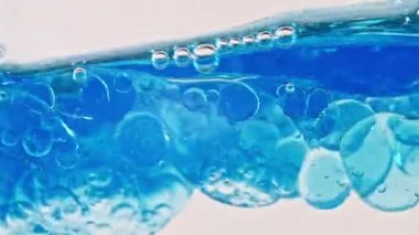 Beyaz Arkaplanda Baloncuklu Mavi Dalga Suyu. Temiz Mavi Su 'da oksijen kabarcıkları. Maden Suyu. Oksijenle zenginleştirilmiş su. Yavaş Hareket Hareketi. Makro Vuruş.
