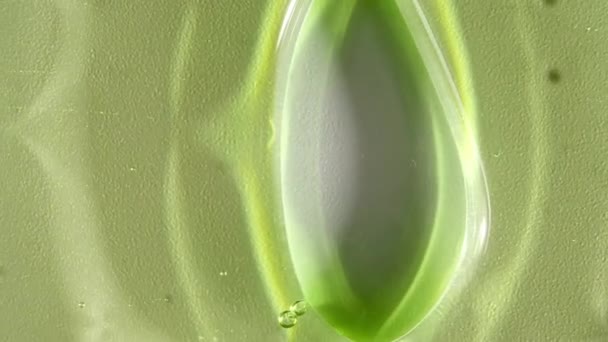 Crème de gel cosmétique transparente verte avec des bulles de molécule coulant sur la surface blanche unie. Macro Shot — Video