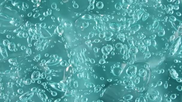 Makroaufnahme von Luftblasen in transparenter kosmetischer Flüssiggelcreme. Blaue Kosmetikflüssigkeit mit Blasen. Zeitlupe — Stockvideo
