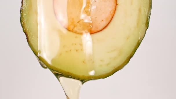 Αργή κίνηση της ροής του χυμού και του ρεύματος πετρελαίου από Avocado φέτα σε λευκό φόντο. Μακρο-βολή. — Αρχείο Βίντεο