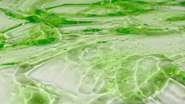 Macro-shot de bulles d'air dans une crème liquide cosmétique transparente. Texture fluide cosmétique verte avec bulles. Mouvement lent — Video