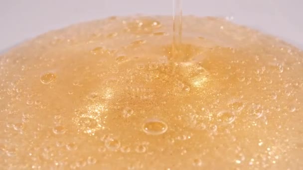 Colpo di rallentamento di olio da versare liquido giallo dorato. Crema Gel, texture cosmetica con bolle. Macro Shot. — Video Stock