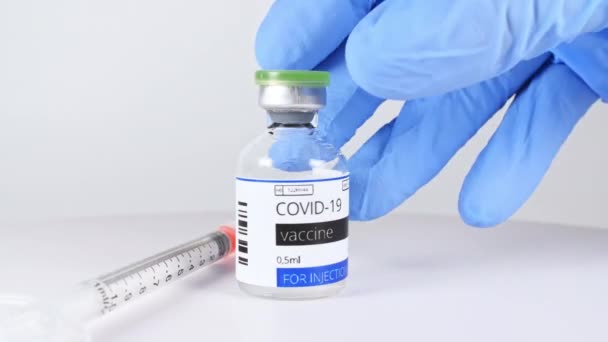 COVID-19 Un vaccin entre les mains d'un chercheur, un médecin met sur la table une seringue et une bouteille de vaccin contre le coronavirus. — Video