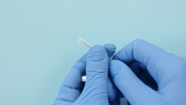 COVID-19 Vacina em Mãos de Investigador. Luvas azuis de mão Enchendo uma seringa com vacina Sarampo, Coronavírus, covid-19. — Vídeo de Stock